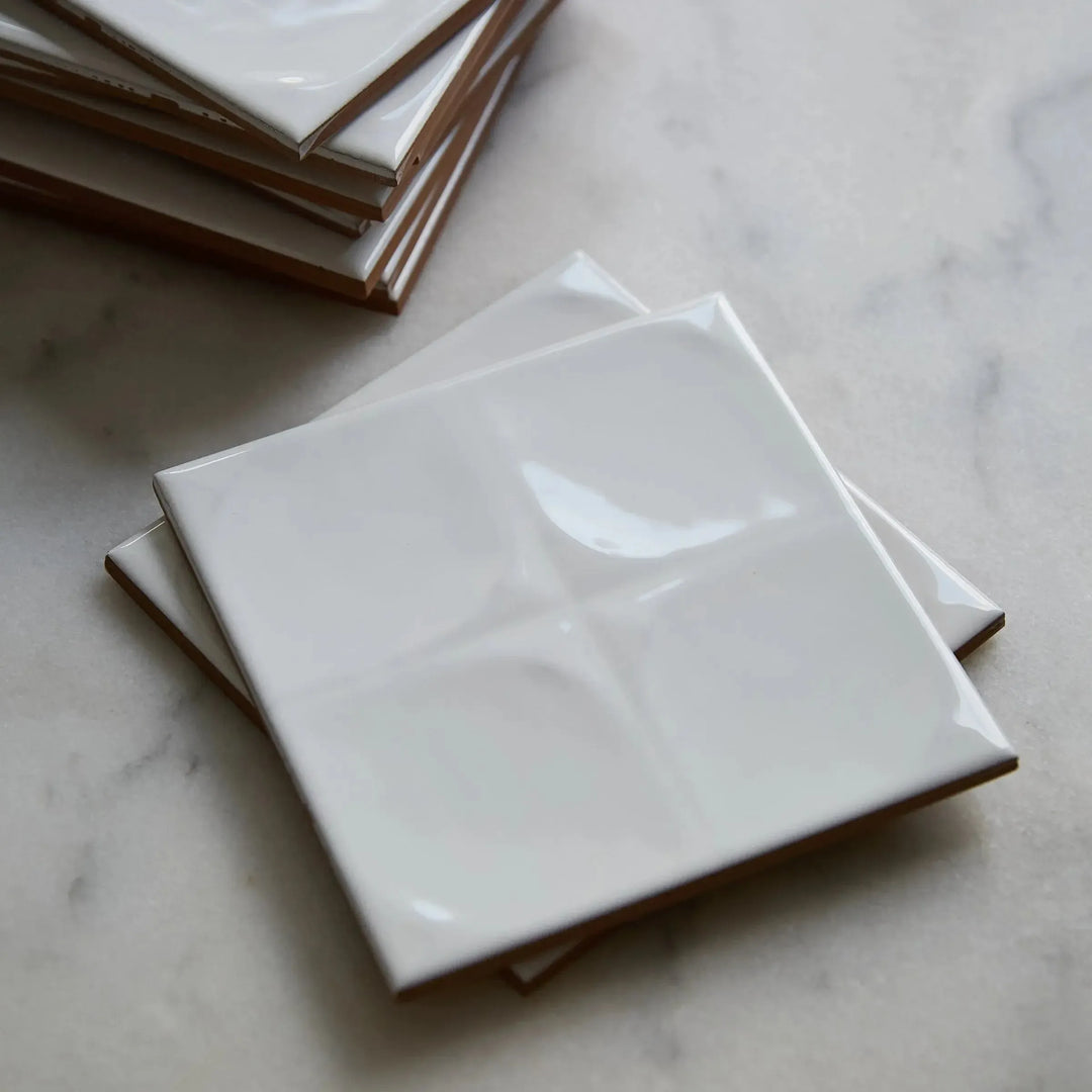oslo wall white 13 cm x 13 cm clearance stack of oslo wall white relief tiles on marble showing the terracotta body at the tile edge