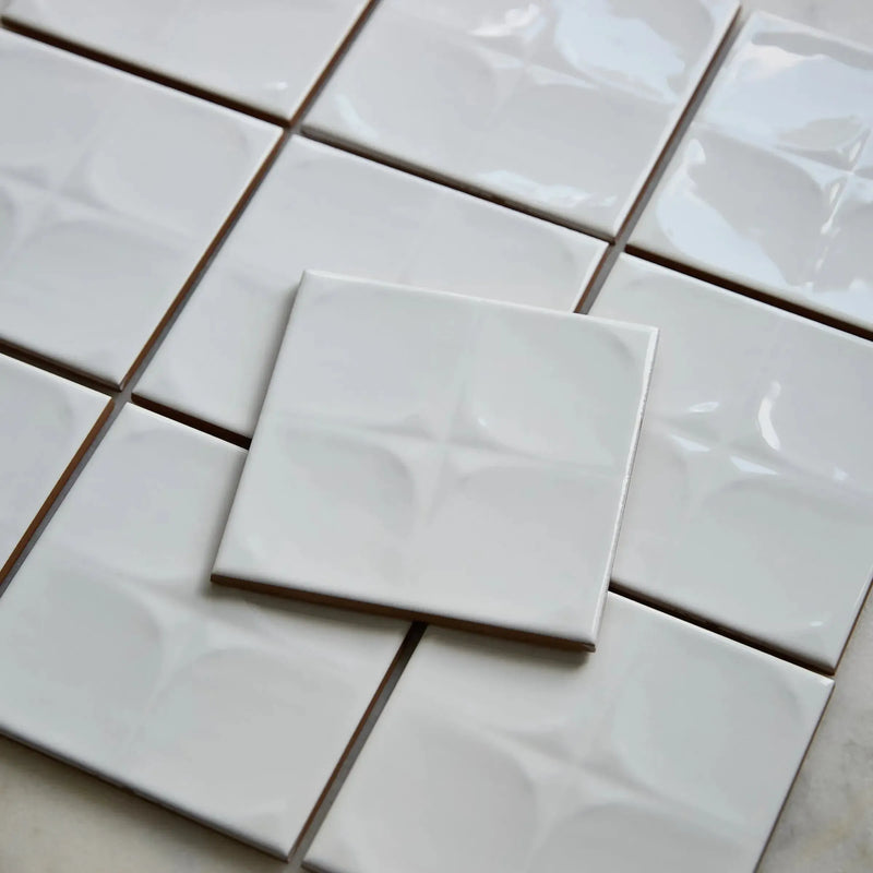 oslo wall white 13 cm x 13 cm clearance oslo wall white tiles viewed at an angle showing the glossy white glaze catching the light across the relief pattern