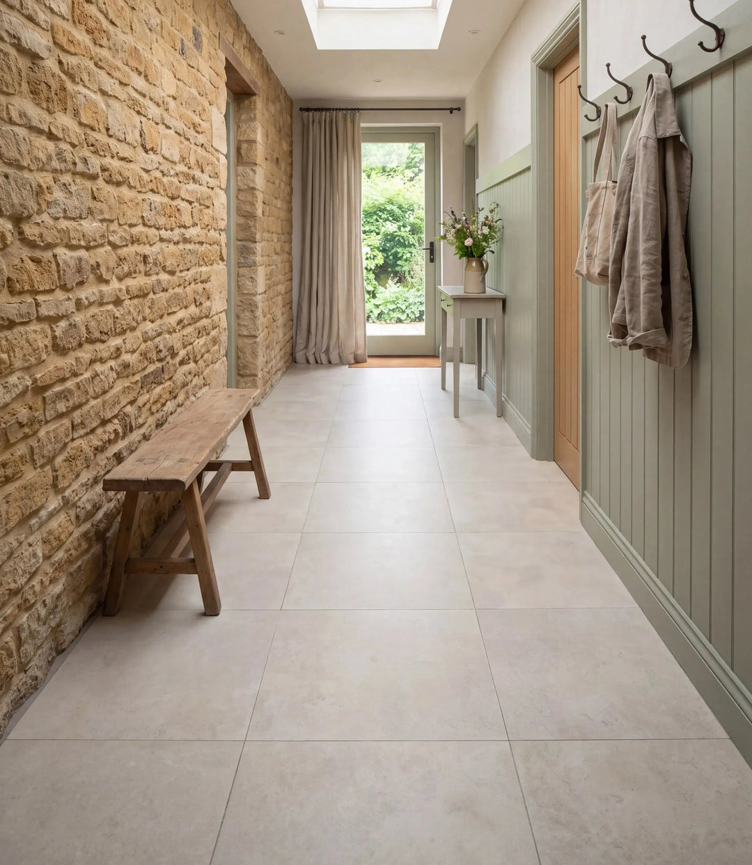 reynoldston satin 60cm x 60cm porcelain floor tiles in a boot room hallway with exposed stone wall sage green panelling and a rustic bench
