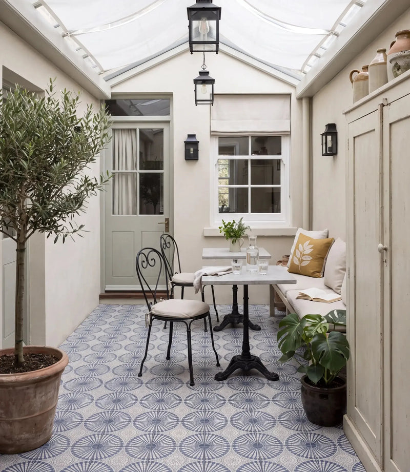 solstice indigo 20 x 20cm solstice indigo tiles in a glazed garden room with bistro table iron chairs olive tree lanterns and cushioned bench